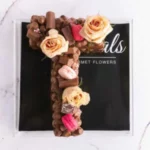 Alphabet initial letter cake decorated with chocolate, roses and macarons in the letter T, made to order from Petals Gourmet Flowers.